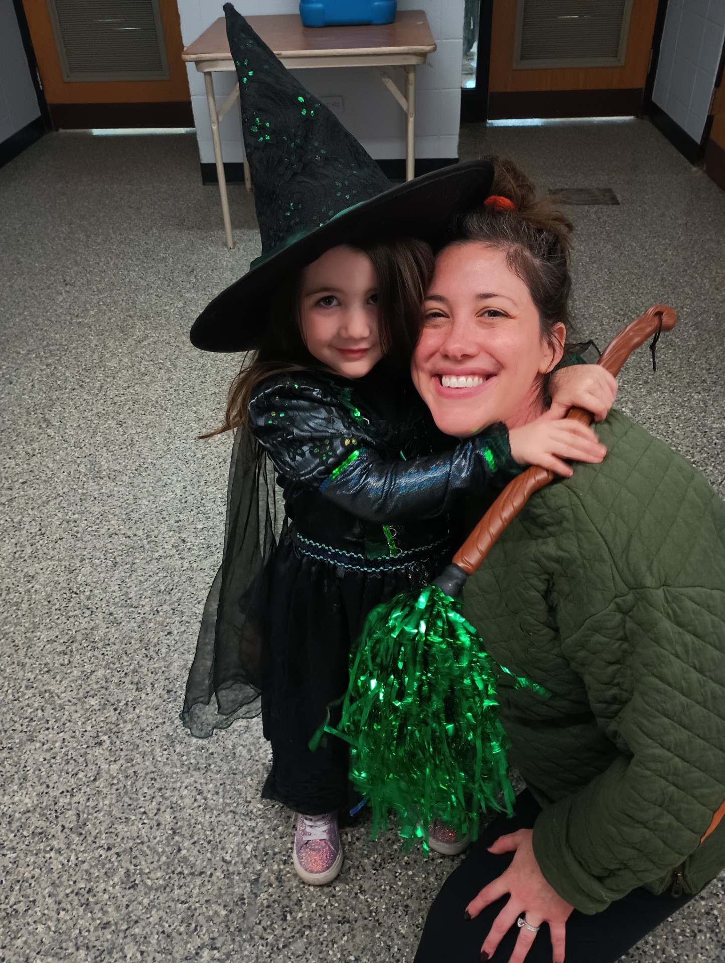 Photograph of woman and child in witch costume smiling.